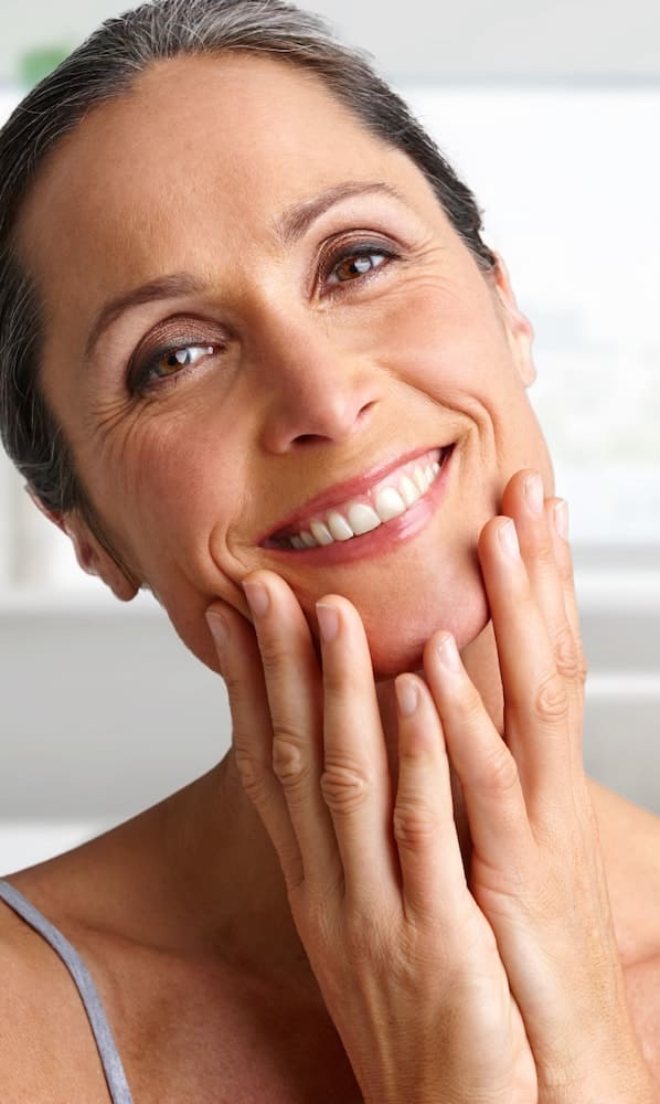 Older woman touching her face and smiling