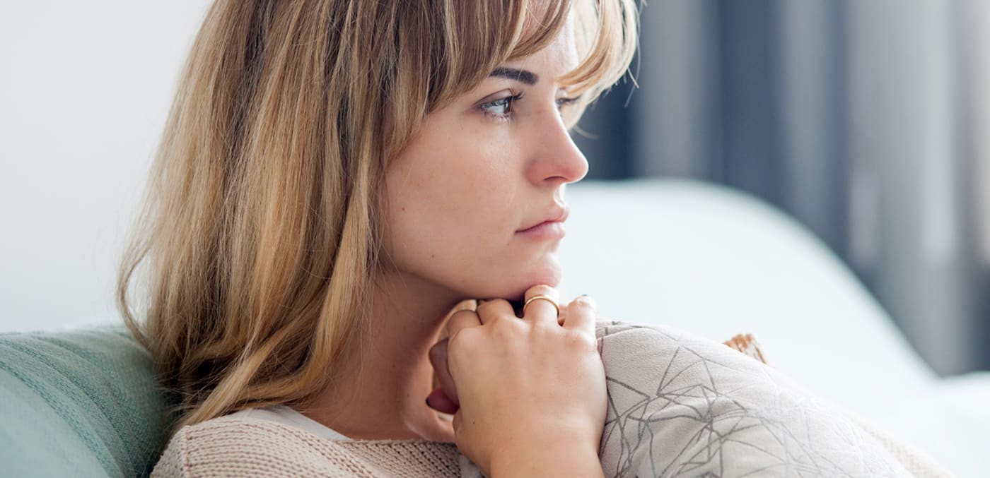 Concerned-looking woman sitting on her couch