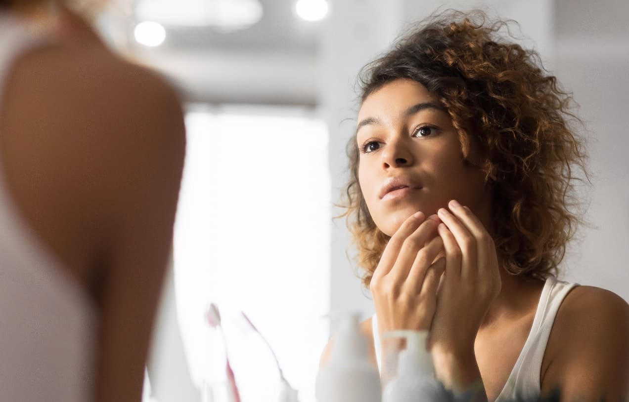 Woman inspecting her face and skin in the mirror