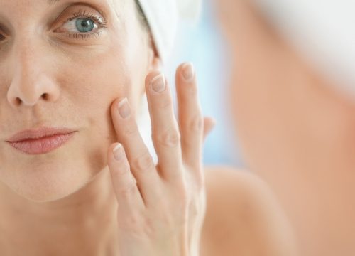 Older woman looking at her skin in the mirror after TempSure® Envi treatments
