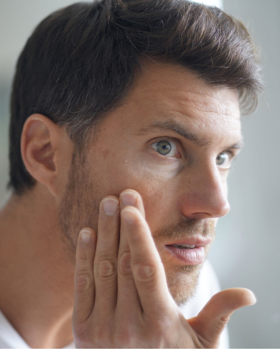 Man checking out his face in the mirror