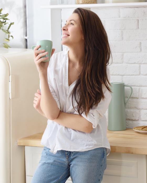 Brunette woman holding a cup of coffee in her living room