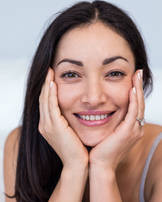 Woman with dark hair resting her face in her hands