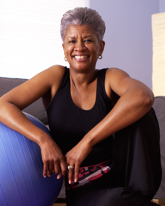 Smiling older woman sitting next to a exercise ball