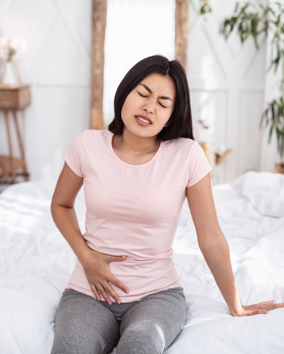 Woman in pain sitting on her bed