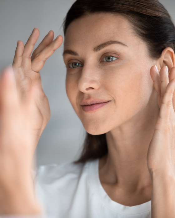 Woman looking at her face and skin in the mirror