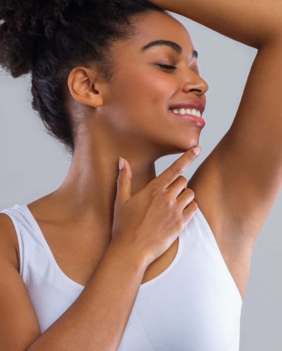 Woman with a hairless armpit touching her face